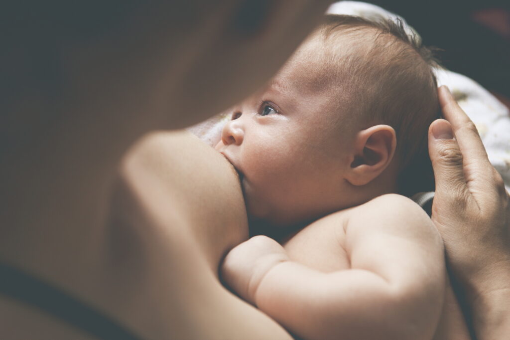 Mother holding and breast-feeding little baby