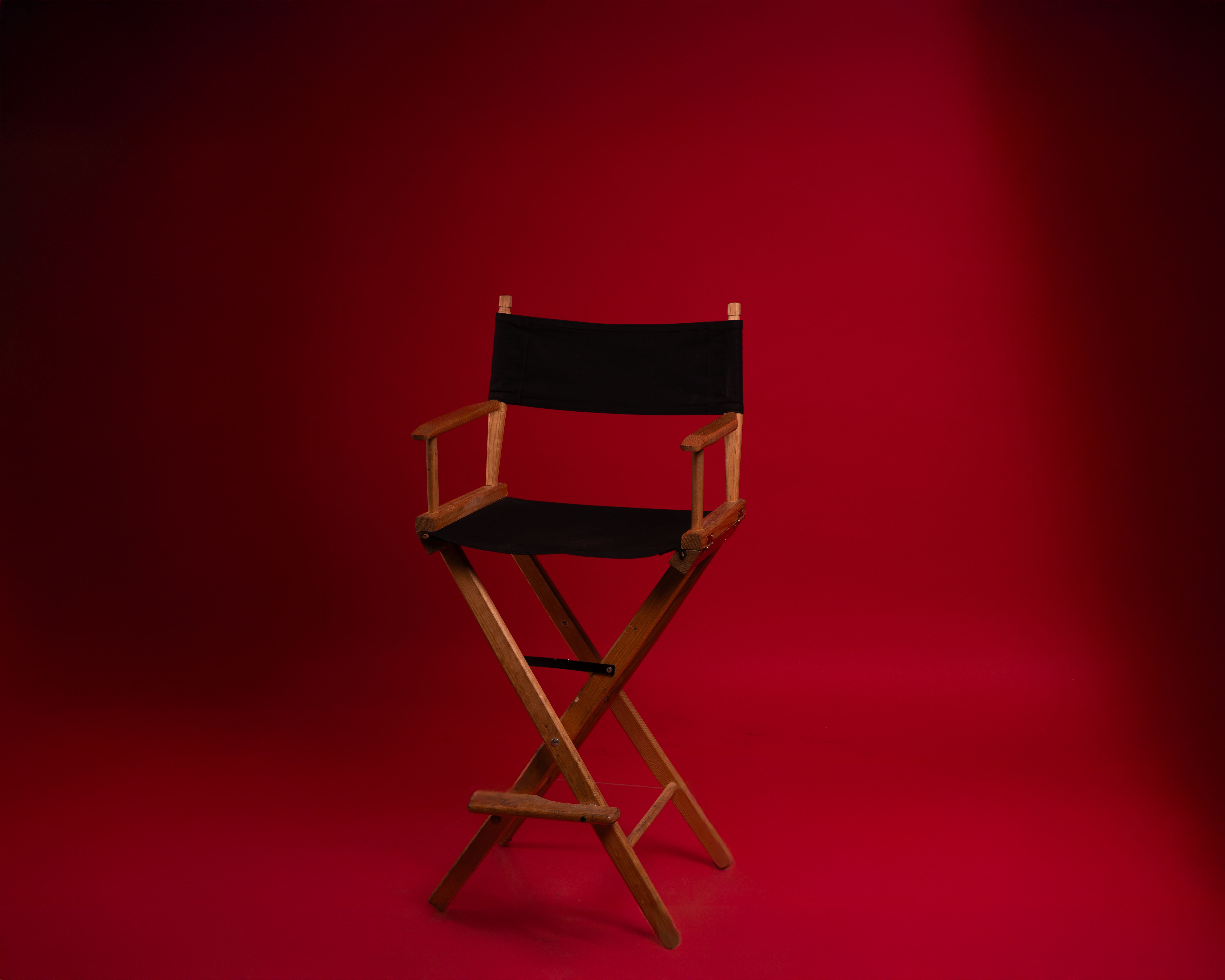 A wooden director's chair against a vibrant red backdrop, symbolizing film industry authority