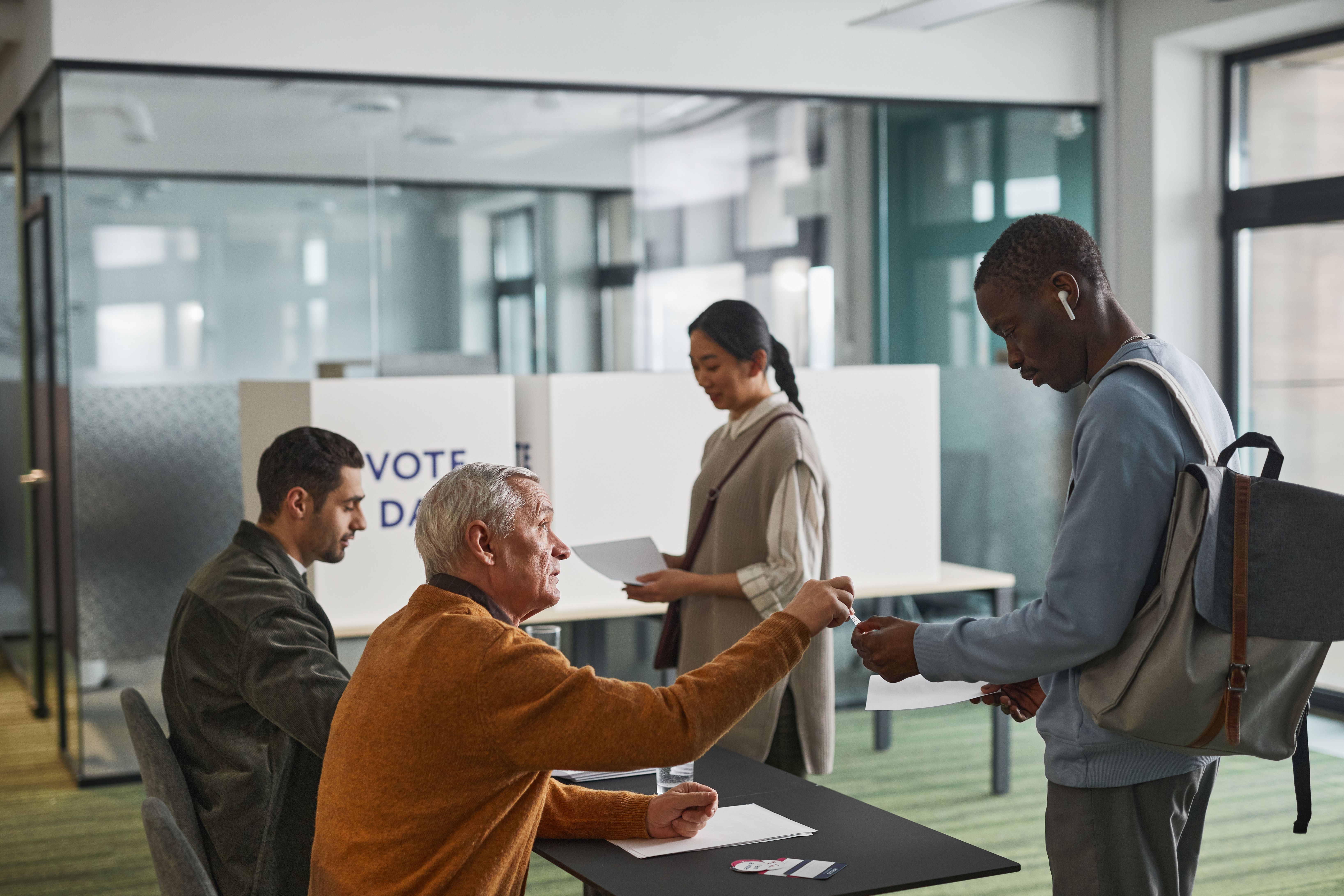 Diverse group of citizens voting at an indoor polling station on election day