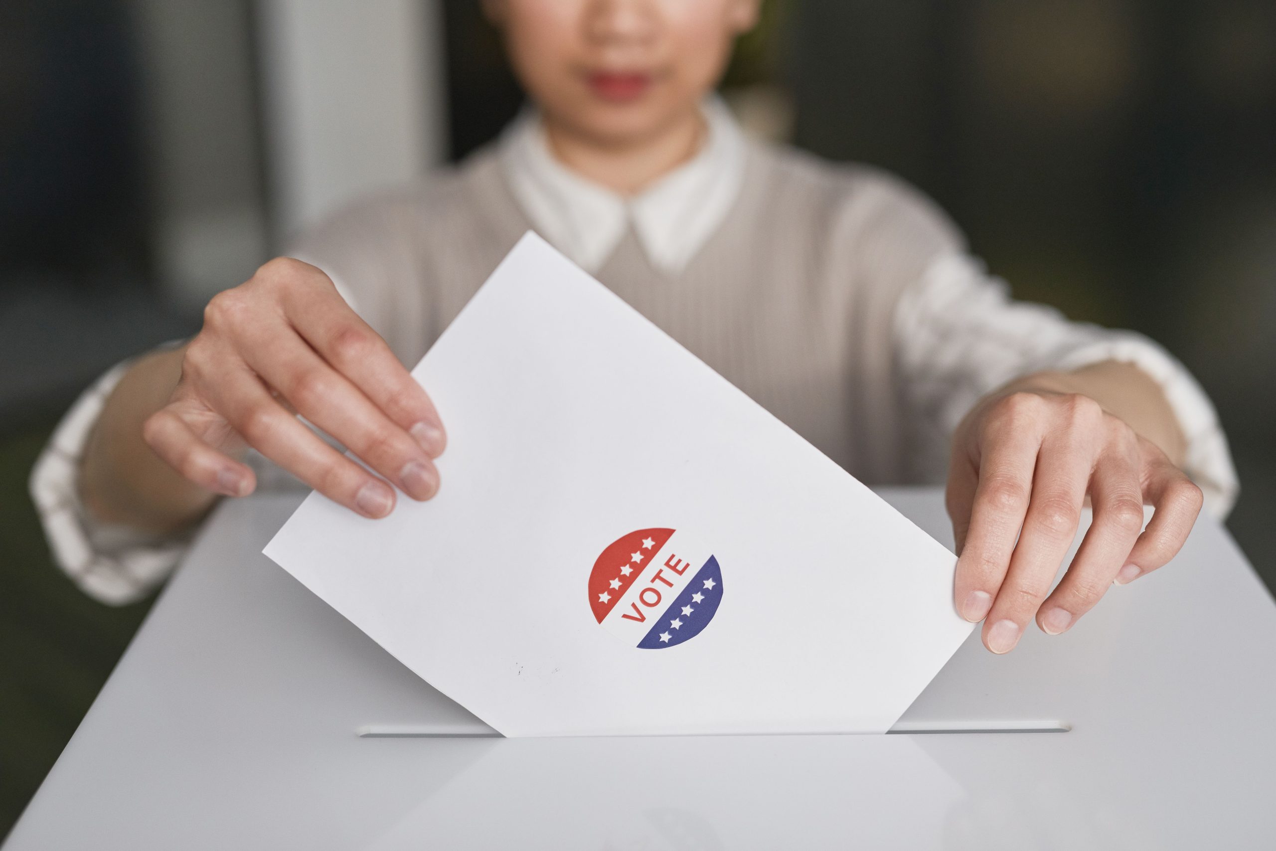 A voter casting a ballot into a ballot box during a regional election, symbolizing democratic participation