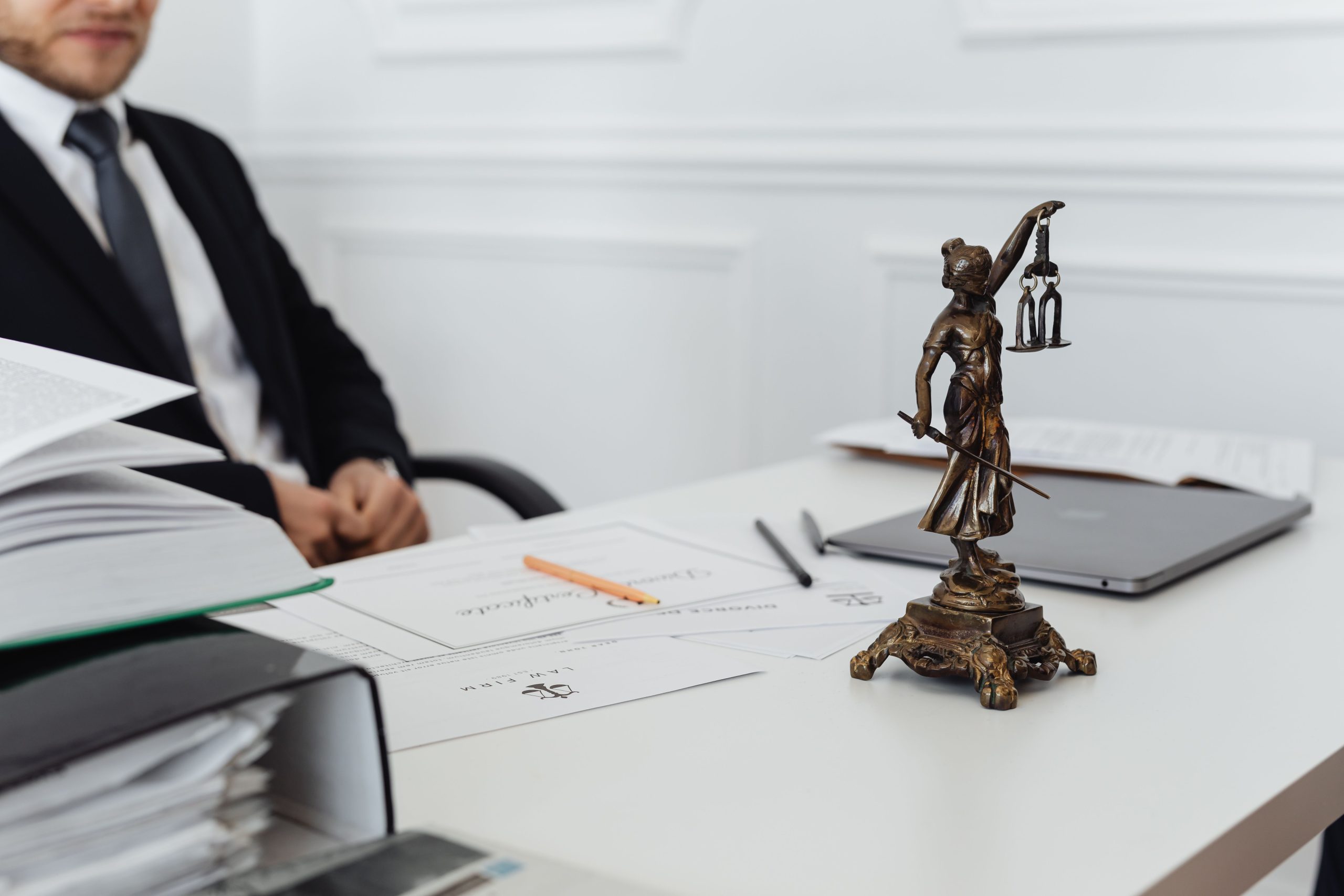 Legal professional's workspace with a Lady Justice statue, documents, and a laptop, representing third-party litigation funding